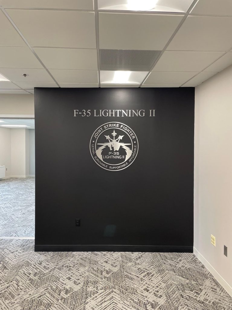 F-35 Lightning II lettering and emblem on a dark office wall.