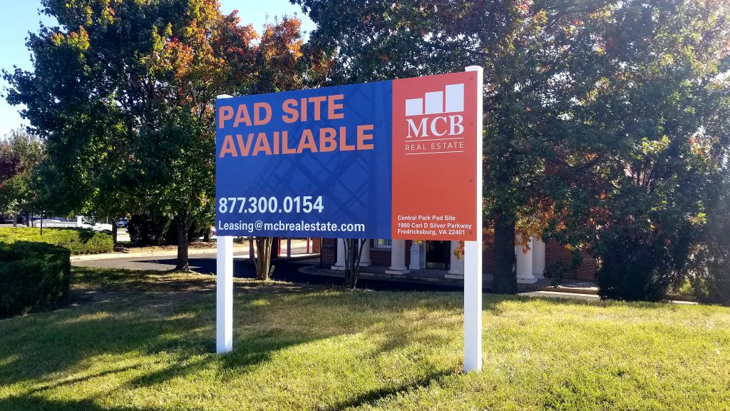 Pad Site Available leasing sign mounted on two posts beside a road.