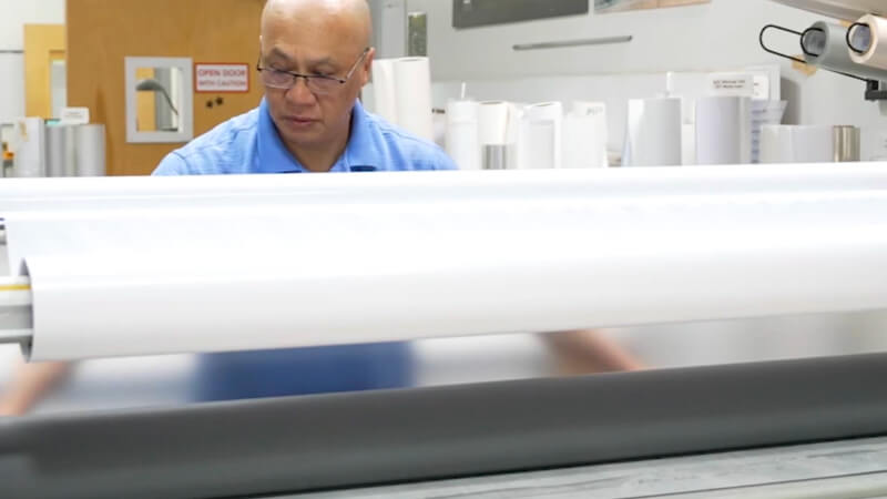 EPI-Colorspace team member operating a laminating machine.