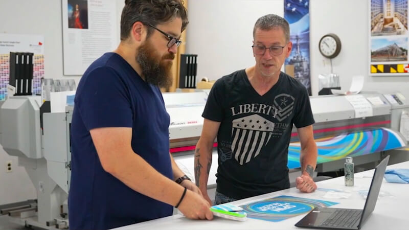 EPI-Colorspace team members inspecting printed graphics at a worktable.