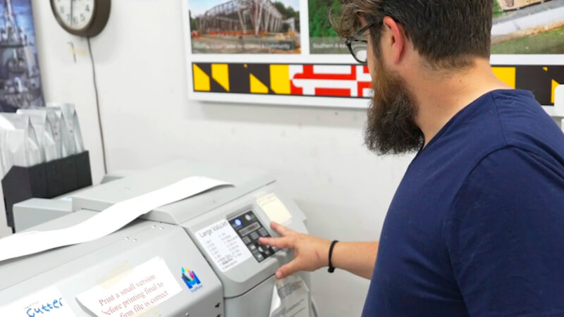 EPI-Colorspace team member operating a large-format printer control panel.
