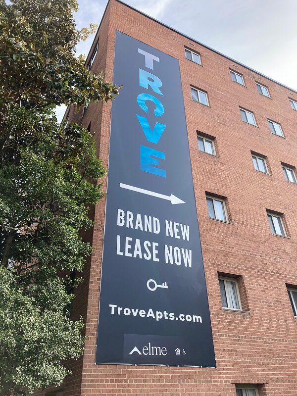 Trove apartment leasing banner mounted on a brick building.