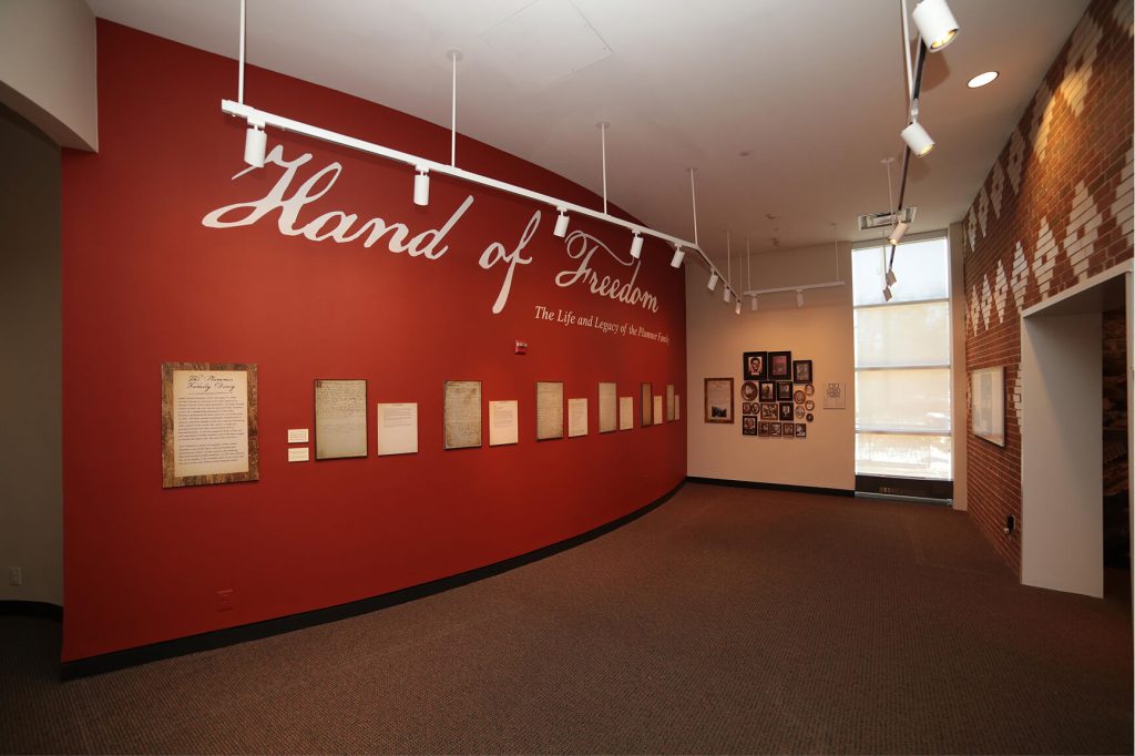 Hand of Freedom lettering and interpretive displays mounted on a red museum wall.