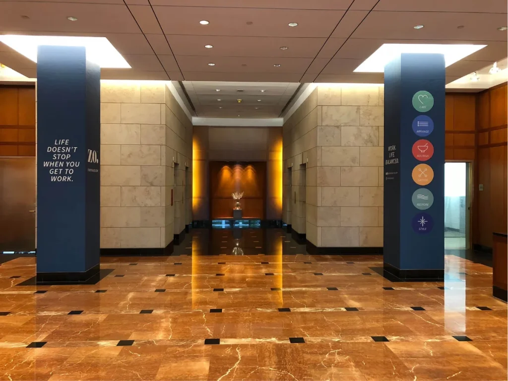 Blue wayfinding pillars with circular icons in an interior lobby.