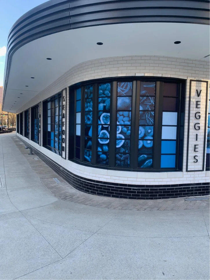 Blue food illustrations and restaurant lettering covering curved storefront windows.