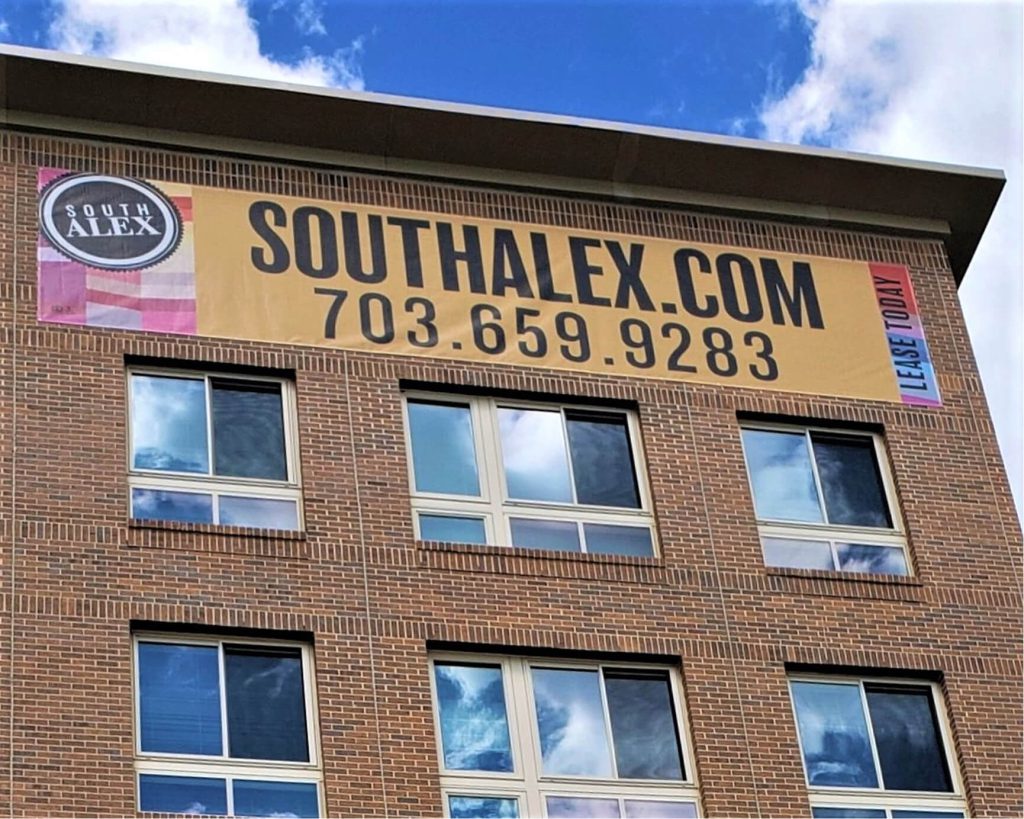 South Alex leasing banner mounted across a brick apartment building facade.